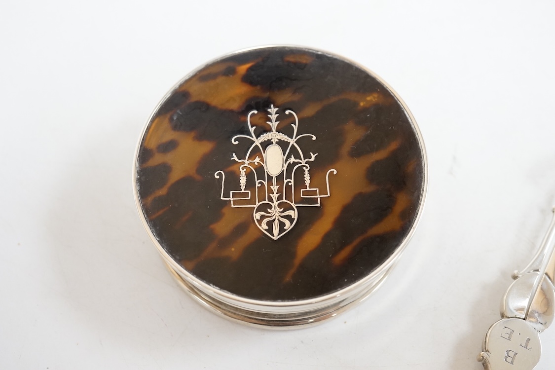A George V silver and tortoiseshell pique mounted circular trinket box, Collett & Anderson, London, 1922, diameter 77mm, together with a pair of 18th century silver sugar nips and a sterling mounted pin cushion, decorate
